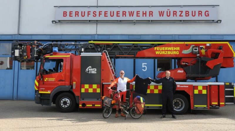 Brandoberinspektor Christoph Hartmann (rechts) überreicht Jörg Richter ein Poloshirt, dass ihn an seine Radtour vom Mittelmeer über die Alpen nach München erinnern soll.