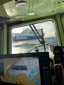 Sie sehen durch ein Bootsfenster ein Schiff der Seenotrettung.