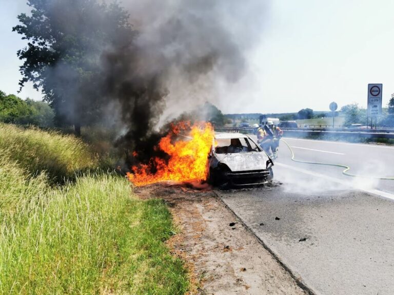 Lagebild: Brennnendes Auto und Böschungsbrand am Fahrbahnrand der A1.