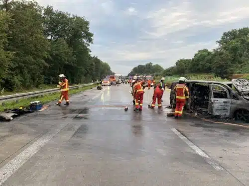 Nach den Rettungsmaßnahmen: Einsatzkräfte reinigen die Fahrbahn mit Stoßbesen.