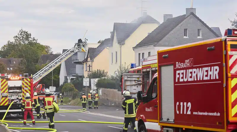 Blick auf das brennende Mehrfamilienhaus mit Drehleiter und GW-N