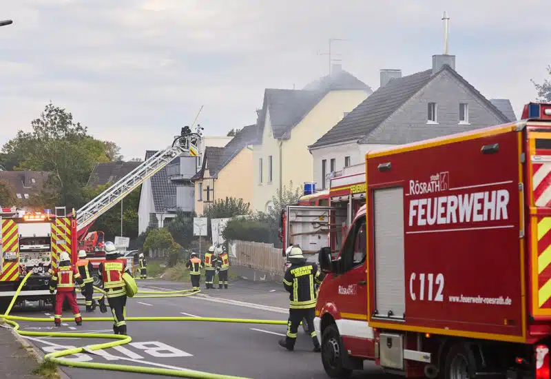 Blick auf das brennende Mehrfamilienhaus mit Drehleiter und GW-N