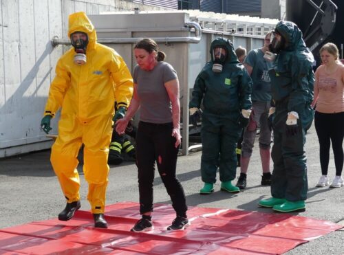 Menschenrettung: Einsatzkräfte in Vollschutzanzügen bringen die Verletzten zur Dekontaminationseinrichtung.
