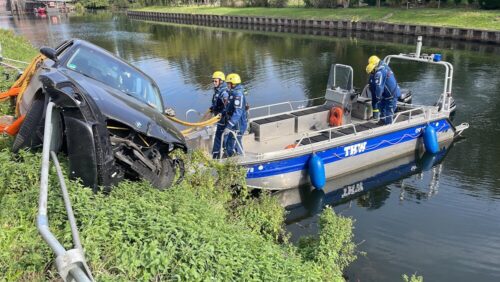 Pkw in Kanalböschung: Vom Boot aus setzen die Einsatzkräfte des THW einen Anschlagpunkt für die anschließende Kranbergung. (Foto: Feuerwehr Kleve)